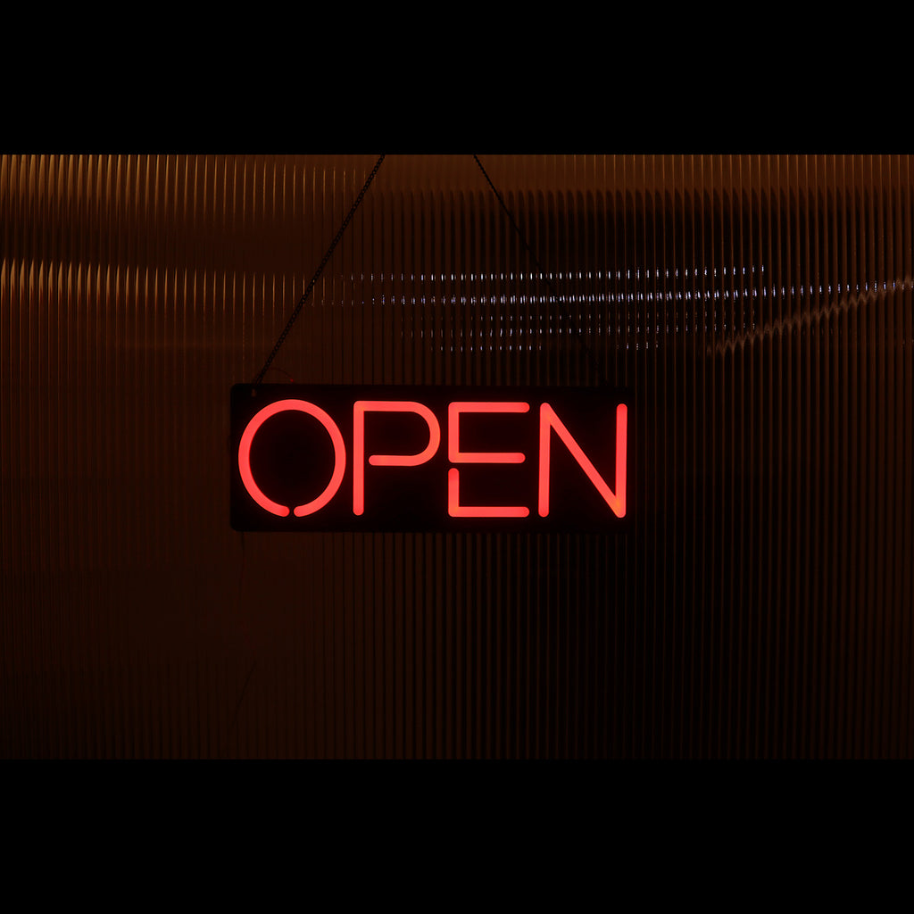 a lighting red open neon sign hanging