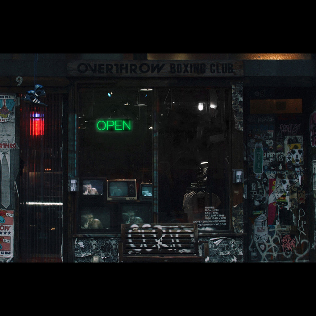 a lighting green open neon sign hanging on a club window