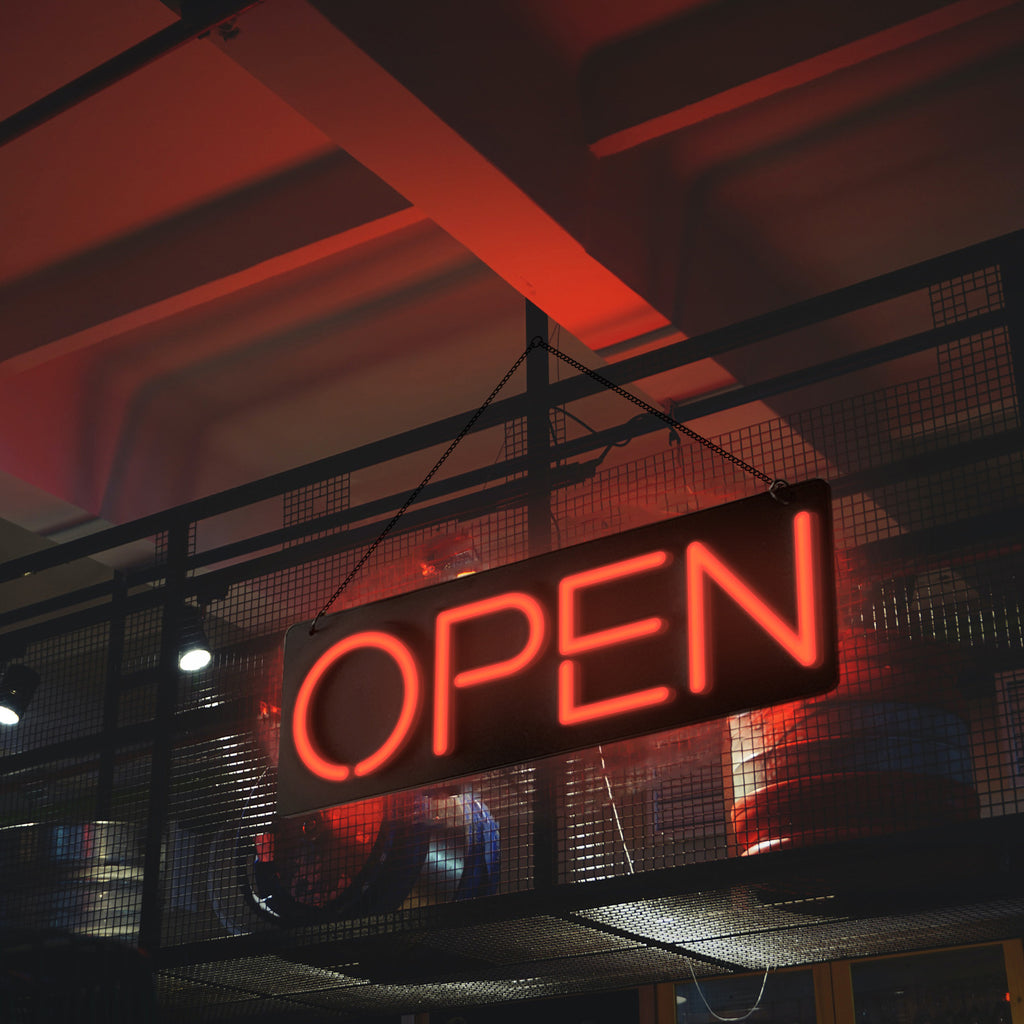 a lighting red open neon sign hanging